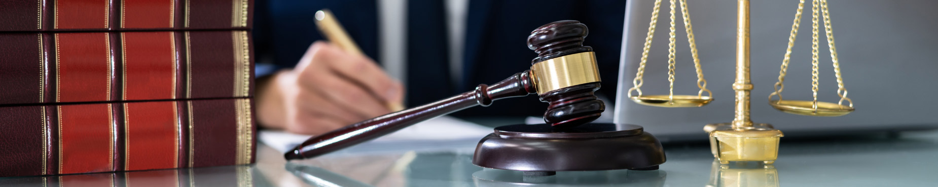 lawyer behind a desk with books, a gavel, and a scale of justice