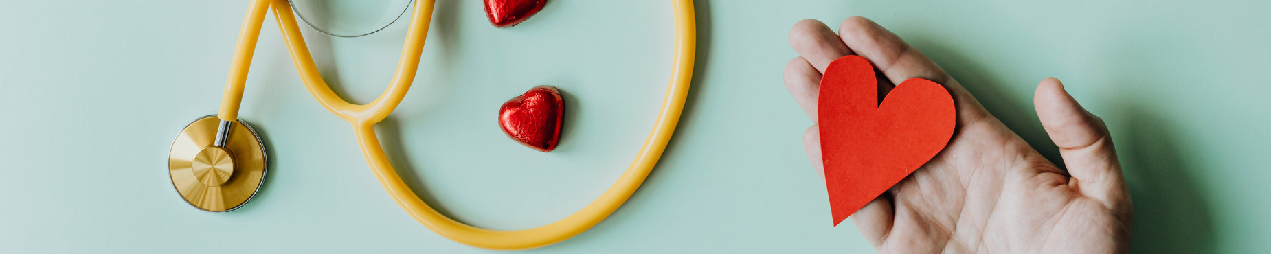 a stethoscope and a hand holding a paper heart