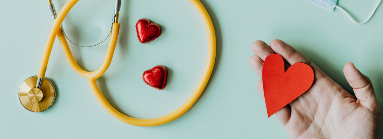 a stethoscope and a hand holding a paper heart