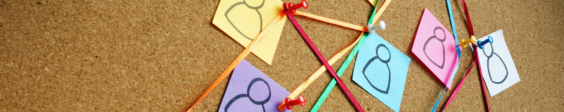 a cork board with post its of people connected with string and push pins