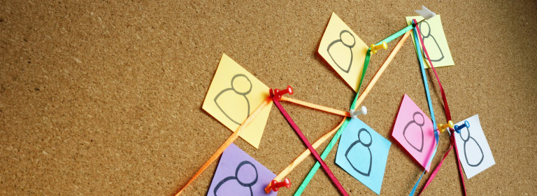 a cork board with post its of people connected with string and push pins