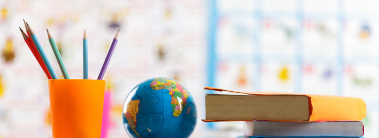 a cup of pencils, a globe, and pencils in a classroom