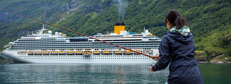 Woman fishing in front of a cruise ship